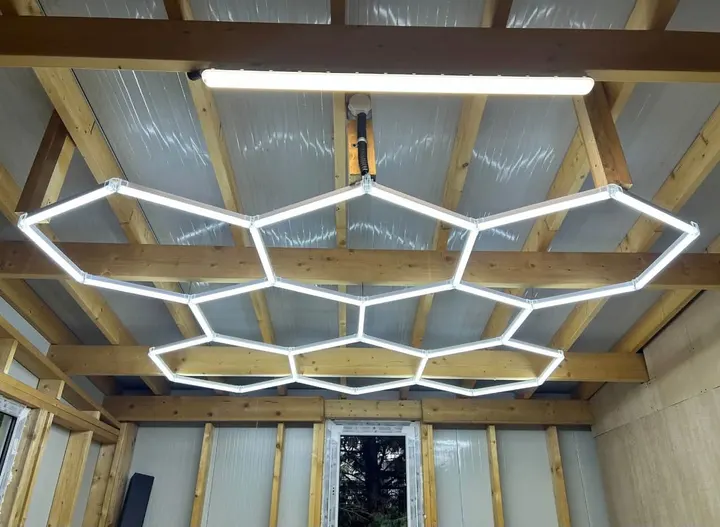 Corpuri de iluminat LED în formă de hexagoane, montate sub grinzile unui acoperiș de lemn