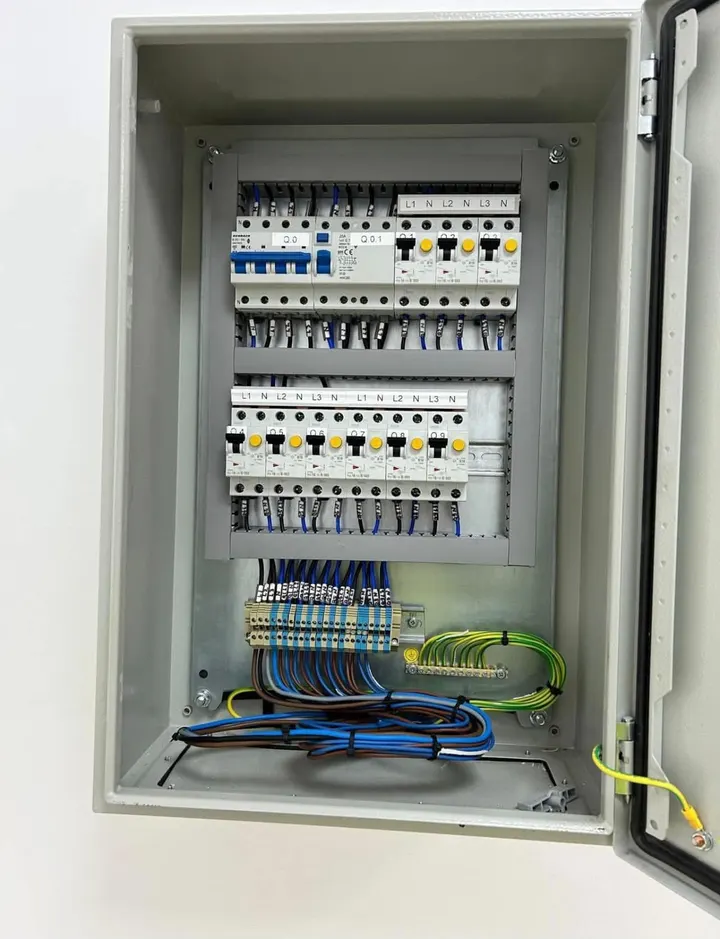 Tablou electric într-un dulap metalic gri, cu aparate de protecție, cabluri colorate și borne